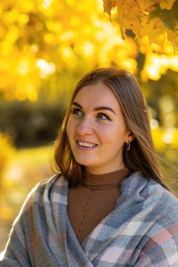 Güzel bir sonbahar parkında gülümseyen mutlu kadın.