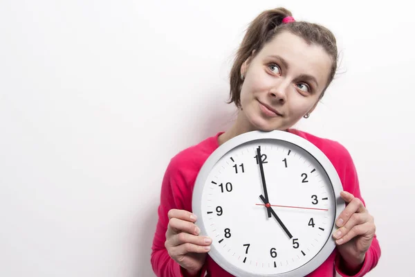 Joven chica atractiva con un reloj en las manos. Concepto de tiempo y mujer . Imagen De Stock