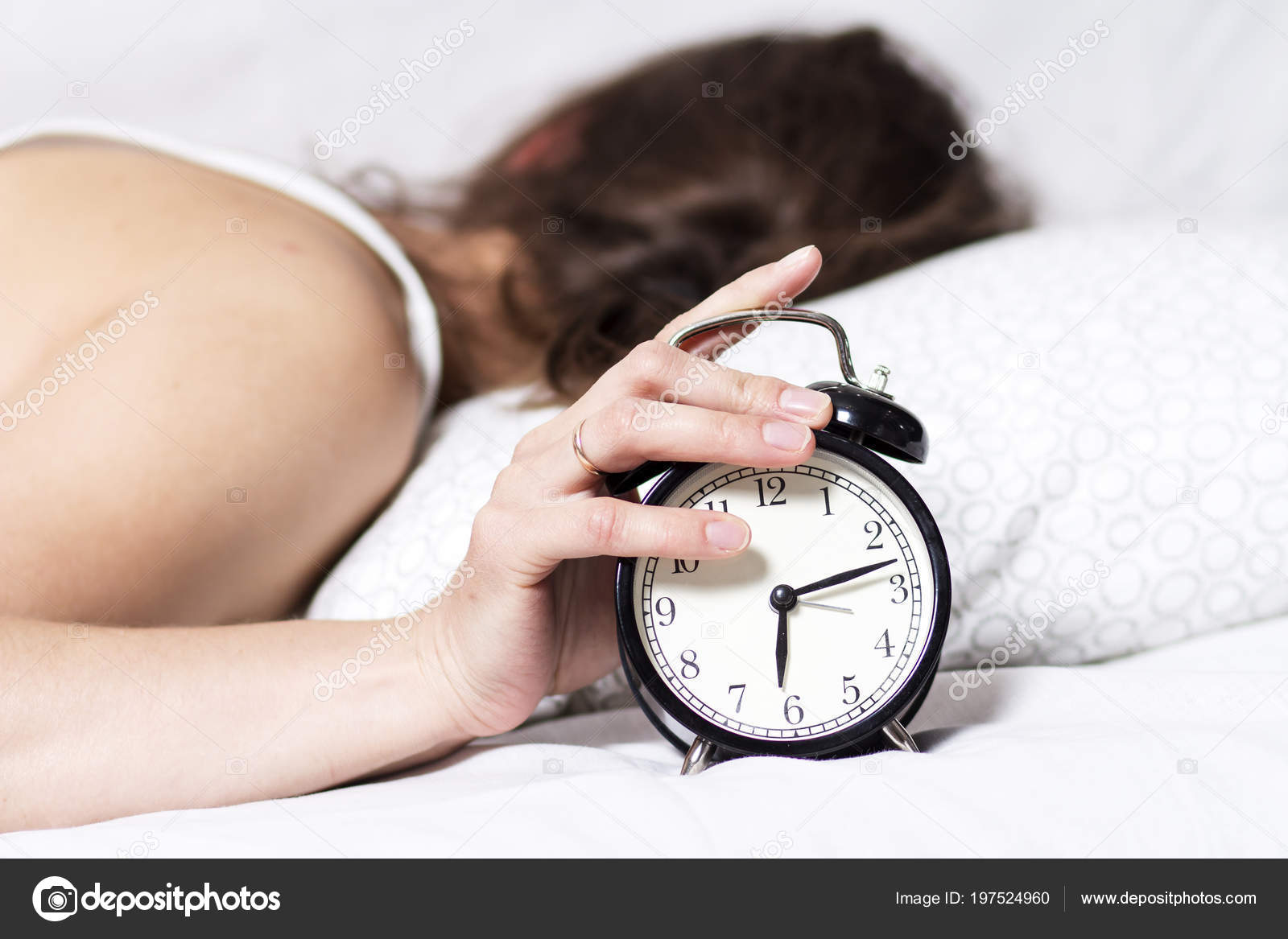 Woman in bed turns off alarm in the morning. woman does not want to