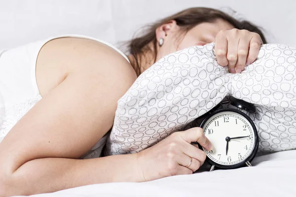 Ragazza nasconde suonando sveglia sotto il cuscino al mattino presto a letto — Foto Stock