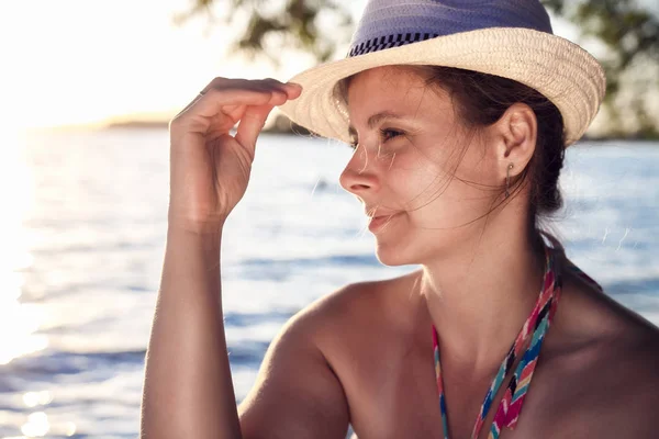 Приваблива засмагла сексуальна мила дама носить капелюх на пляжі на заході сонця в теплий літній вечір. мрійлива витончена жінка на морському пляжі. тихий вечір у морі. Дівчина на фоні заходу сонця. Молода жінка у відпустці . — стокове фото