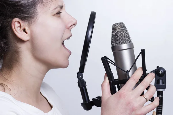 Het meisje is zingen in de studio-microfoon. Opnemen van de zang van een jonge zangeres. — Stockfoto