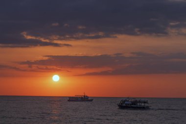 Denizin bir renkli gece gökyüzü ve güneş denize yuvarlak bir disk ile gün batımında tekne ile güzel deniz manzarası.