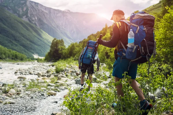 Turistas con mochilas de senderismo en hermoso paisaje de montaña de fondo. Los escaladores caminan a los montes. Grupo de excursionistas caminando en las montañas —  Fotos de Stock