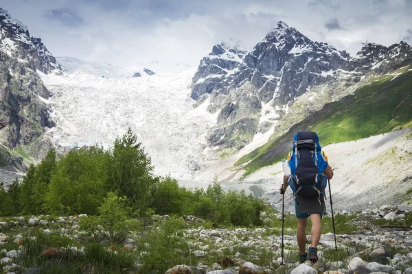 Dağlarda trekking fiyatı. Kayalık dağ karla kaplı dağcı turist sırt çantası ile gider. Boş zaman etkinliği. Dağlar'da yürüyüş. Gezgin adam Caucasus dağda hiking. — Stok fotoğraf
