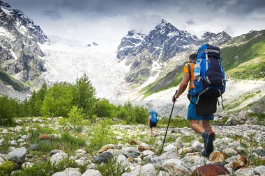 Sırt çantaları hiking ile dağcı Dağı'na git. dağlarda yürüyüş yapanlar. Turistler üzerinde Kayalık Dağları zammı. Boş zaman etkinliği Dağı'nda trek Gürcistan vahşi Svaneti bölgesi. Groupe Hiking