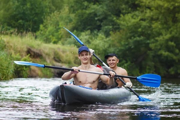 Ruderer werden im Kajak auf dem Fluss entlanggeschwemmt. Zwei Freunde schwimmen an einem strahlenden Sommertag im Boot auf dem Fluss und rudern auf dem Wasser. Aktive Erholung in der Natur. Gruppe von Kanuten auf dem Fluss — Stockfoto