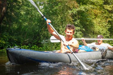 Elinde yaz gününde nehrinde kürek ile iki rowers tekne. Genç çocuklar yüzmek bir kano Nehri boyunca spor. Kayık nehirde rafting. Boş zaman etkinliği. Sağlıklı bir yaşam tarzı. Su spor.