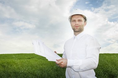 Mimar ile yeni bir inşaat alanında bir beyaz kask çizimlerde portresi.