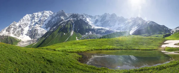 Berglandschaft von Vaneti an einem strahlend sonnigen Sommertag. Bergsee, Hügel bedeckt mit grünem Gras auf schneebedeckten felsigen Bergen Hintergrund. Kaukasusgipfel in Georgien. atemberaubende Aussicht auf die wilde georgische Natur. — Stockfoto