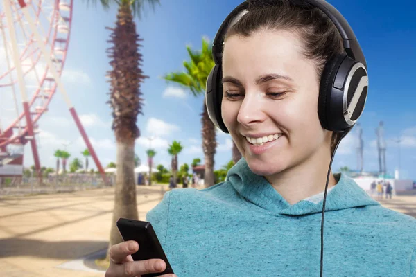 Aantrekkelijk meisje met een speler op een stad straat op een heldere zonnige dag luisteren naar muziek. — Stockfoto