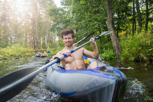 A group of friends in boats sails on river. Kayaking on wild river. Leisure. Rafting on the river by canoe. A young athletic man with oars rowing in boat on the water. Summer rafting season on kayak. — Stock Photo, Image