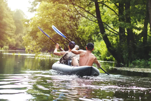 Rafting na rzece w kajaku w sezonie letnim. Aktywny wypoczynek. Dwie osoby w rzędzie łódź z wiosłami. Chłopaki płyniemy wzdłuż rzeki w kajak. Przygody przyjaciół latem nad rzeką — Zdjęcie stockowe