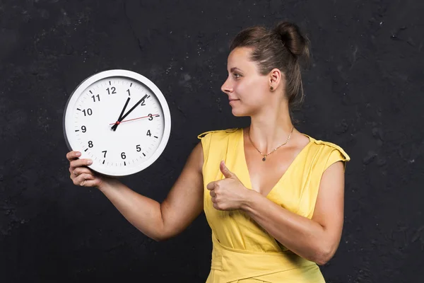 Una giovane donna sta tenendo un orologio. Concetto temporale. Una ragazza con un orologio in mano. Tenere traccia del tempo — Foto Stock