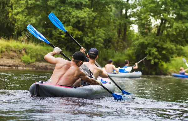 Kayak sul fiume. I giovani stanno facendo rafting lungo un fiume selvaggio in kayak. Vogatori con remi in barca. In canoa. Un gruppo di turisti sta nuotando lungo il fiume in barca. Vogatori vogatori con remi — Foto Stock