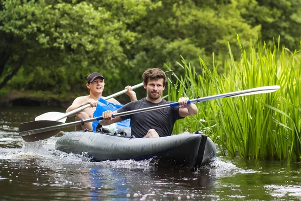 Kajakfahren auf dem Fluss. zwei Freunde in einem Boot, das den Fluss entlang segelt. Ruderer mit Rudern im Kanu. Rafting auf einem Kajak. Freizeit. junge Männer radeln auf einem wilden Fluss. — Stockfoto