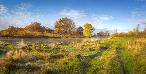 Herbstliche Naturlandschaft. Herrliches Panorama des herbstlichen Flussufers mit Bäumen, Wiese und blauem Himmel an sonnigen Tagen. goldene Natur im Oktober. bunte Blätter und Gras am Ufer des Flusses. Szenenherbst. Herbst. — Stockfoto