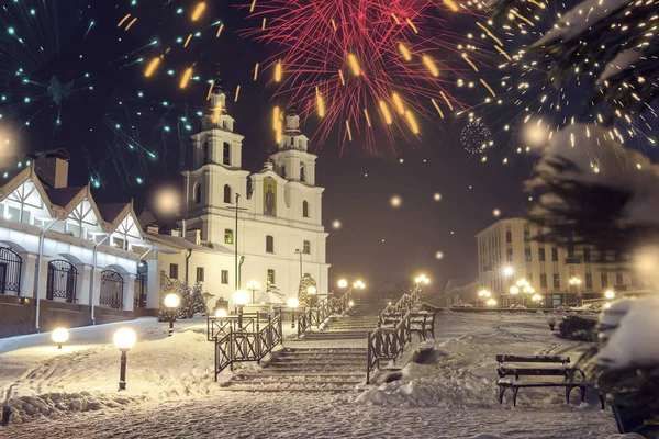 Minsk, Bielorrusia. Los fuegos artificiales de fiesta celebran la Navidad y el Año Nuevo en Minsk. Paisaje de la famosa iglesia catedral ortodoxa en la noche de Año Nuevo, Bielorrusia. Paisaje urbano con luces brillantes y fuegos artificiales . — Foto de Stock