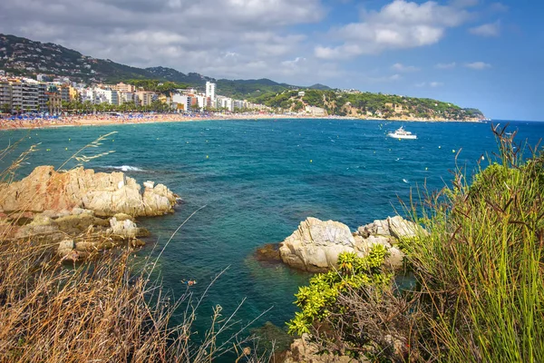 Plaży Lloret de Mar, Costa Brava, Katalonia, Hiszpania. Morze, skały na Lloret de Mar platja. Zobacz na hiszpański ośrodek miasta na wybrzeżu w słoneczny letni dzień — Zdjęcie stockowe