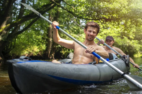 Kajakfahren. glückliche Freunde, die zusammen auf dem Fluss paddeln und lächeln. Sportliche Männer im Kanu schwimmen in einem Boot mit Rudern. Freizeitaktivität. Kanufahren auf wildem Fluss im Dschungel. — Stockfoto