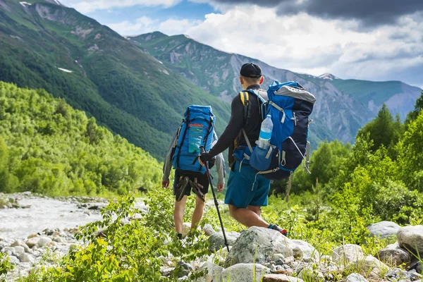 Turistas em mountain trek. Dois amigos nas montanhas. Caminhadas em colinas e montes. Caminhantes caminha no caminho rochoso. Trekking nas montanhas do Cáucaso. Caminhada em Svaneti, Geórgia. Atividade de lazer na natureza selvagem . — Fotografia de Stock