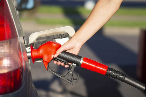 Mão detém pistola de gasolina no tanque de combustível no posto de gasolina vista close-up . — Fotografia de Stock