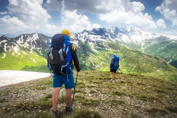 Trilha de caminhadas com turistas na cordilheira. Trekking nas montanhas. Dois caminhantes caminham em montanhas nevadas. Atividades de lazer em Svaneti, Geórgia. Turismo desportivo no Cáucaso . — Fotografia de Stock