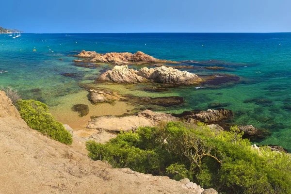 Csodálatos a kilátás a Platja de Santa Cristina, Lloret de Mar, a Costa Brava, Spanyolország. Sziklák a nyári homokos strand a Földközi-tenger türkizkék vízben. Paradise lagoon spanyol üdülőhelyen — Stock Fotó