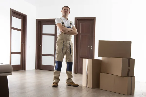 Carregador com caixas de papelão no apartamento. Mover em casa. Serviços de recolocação homem . — Fotografia de Stock