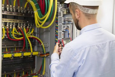 Elektrikçi mühendis olarak iş yüksek gerilim enerji elektrik hattı teftiş yapan kablo bağlantı endüstriyel dağıtım fuseboard. Hizmet adam multimetre ile