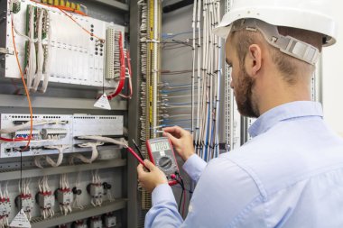 elektrikçi teknisyen sigorta kutusunda. Denetim Masası'nda bakım mühendisi. İşçi Otomasyon cihazları test ediyor. Mühendislik Elektrik istasyonu. Elektrik adam elinde multimetre ile. Hizmet.