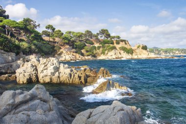 Güzel manzarası kayalık plaj Lloret de Mar, Costa Brava, İspanya. Kayalar ve denizde Lloret de İspanyol sahil şeridi üzerinde taşlar. Güneşli Akdeniz doğa manzara.