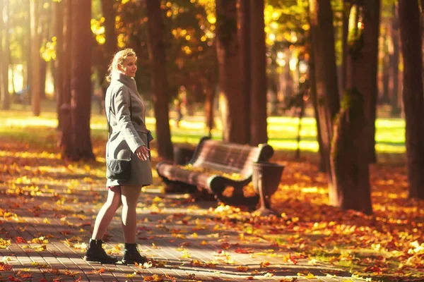 Giovane donna cammina al colorato parco autunnale. Pomeriggio soleggiato nel parco forestale autunnale. La ragazza si rilassa nel vivido parco. Donna trascorre del tempo all'aperto — Foto Stock