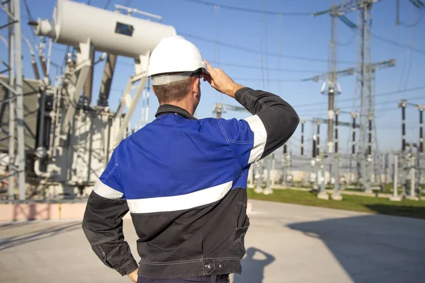 Engenheiro eletricista na estação de energia elétrica olhar para equipamentos industriais. Técnico em capacete na subestação electro. Exame dispositivos de alta tensão . — Fotografia de Stock