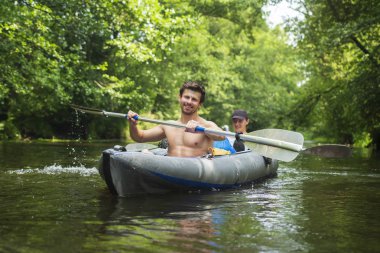 Spor eğlence kayık üzerinde. Kano eğlence Turizm. İki arkadaş tekne kürek ile yüzmek. Kayak. Kano. Erkekler yeşil vahşi ormanda kayık içinde yüzüyor