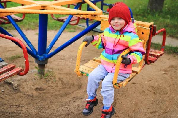 Bambina bambina sulla giostra nel parco giochi. Il bambino sta cavalcando su un'altalena . — Foto Stock