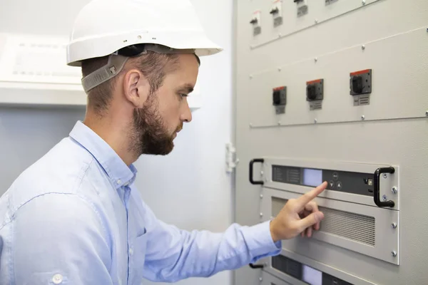 Electricista hombre de servicio configura de controlador eléctrico. Trabajos de mantenimiento. Servicios de ingeniería en complejo industrial. Dispositivo de ajuste. El hombre ajusta los dispositivos. Equipos de examen del trabajador . — Foto de Stock