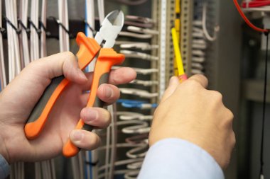 Elektrikçi elektrik sigorta kutusu içinde elinde elektrikli aletler.