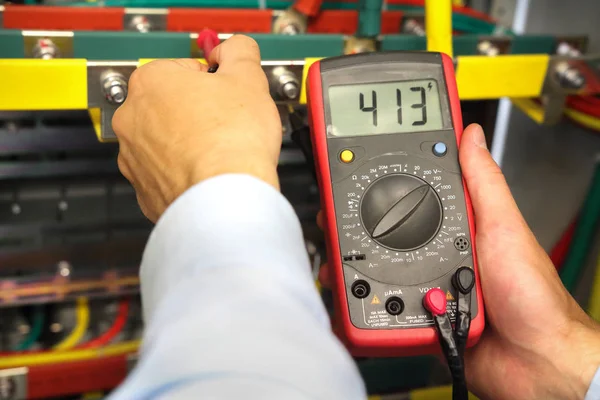 Electrician measures voltage in fuse box. Engineer with electrical tools examining electrical cabinet. — Stock Photo, Image