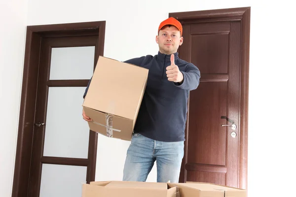Delivery man with cardboard box shows thumb up