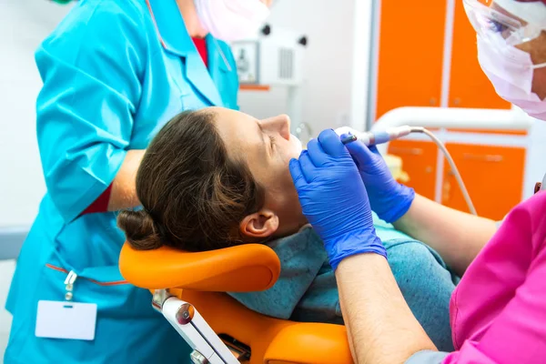 Equipo de dentistas trata los dientes al paciente en la clínica dental . —  Fotos de Stock