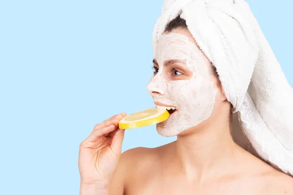 Vrouw met crème gezichtsmasker bijt schijfje grapefruit — Stockfoto