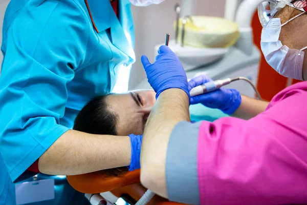 Equipo de dentistas trata los dientes en la clínica dental —  Fotos de Stock