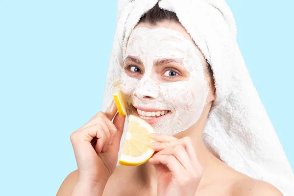 Lächelndes schönes Mädchen mit Gesichtscreme-Maske und Zitronenscheibe. — Stockfoto