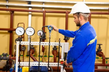 Teknisyen alt endüstriyel tesis üzerinde ölçümler basınç manometreler denetler.