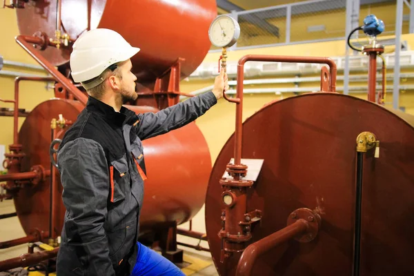 Technician checking gauge of pressure on oil tanks