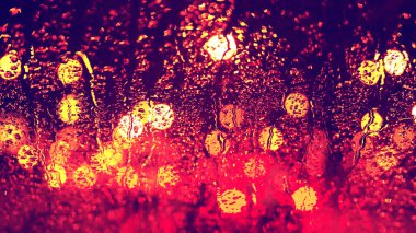 Islak parlayan şehir sokak ışıkları karşı araba camına düşüyor