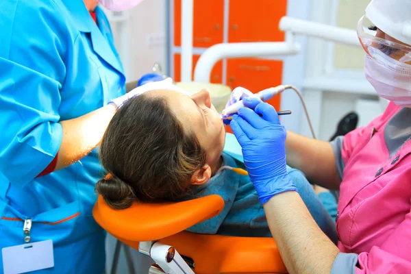 Diş hekimi ve yardımcı matkaplar dişlerini hastanın — Stok fotoğraf