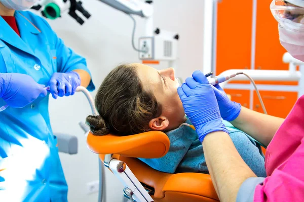 El dentista y su asistente tratan los dientes del paciente en el consultorio dental . —  Fotos de Stock