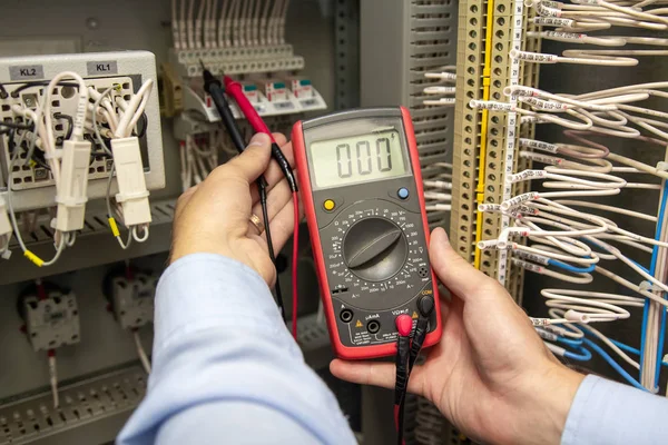 Eletricista com testador multímetro em mãos trabalhando em caixa elétrica . — Fotografia de Stock